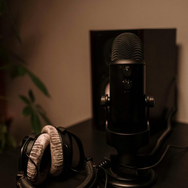 pexels-photo-6892712-6892712 Close-up of a microphone and headphones on a desk, ideal for podcasting or audio production.